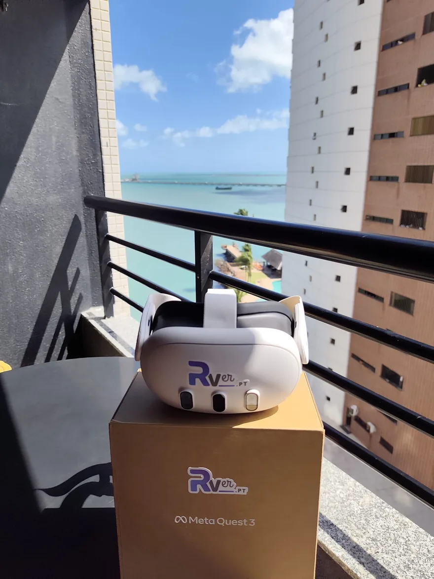 White Meta Quest 3 headset with the RVer.pt logo, resting on its box on a balcony overlooking the sea in Fortaleza.